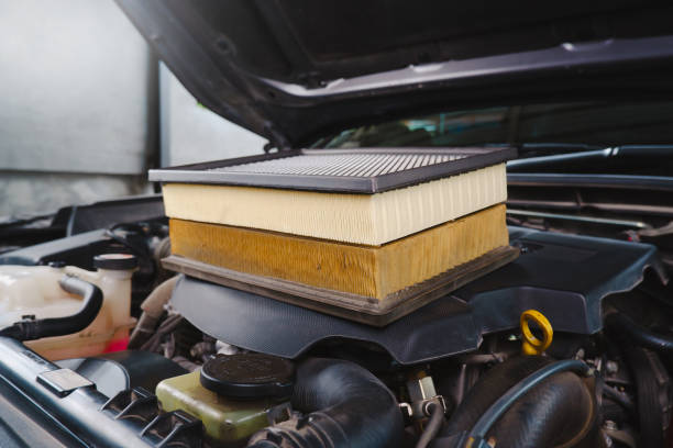 Comparing new and used car air filters placed on the engine